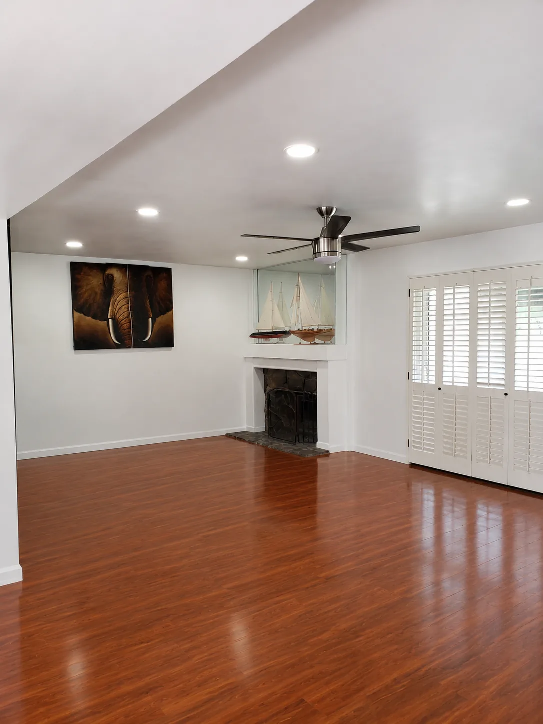 Finished wood flooring in a remodeled living room with fireplace and ceiling fan