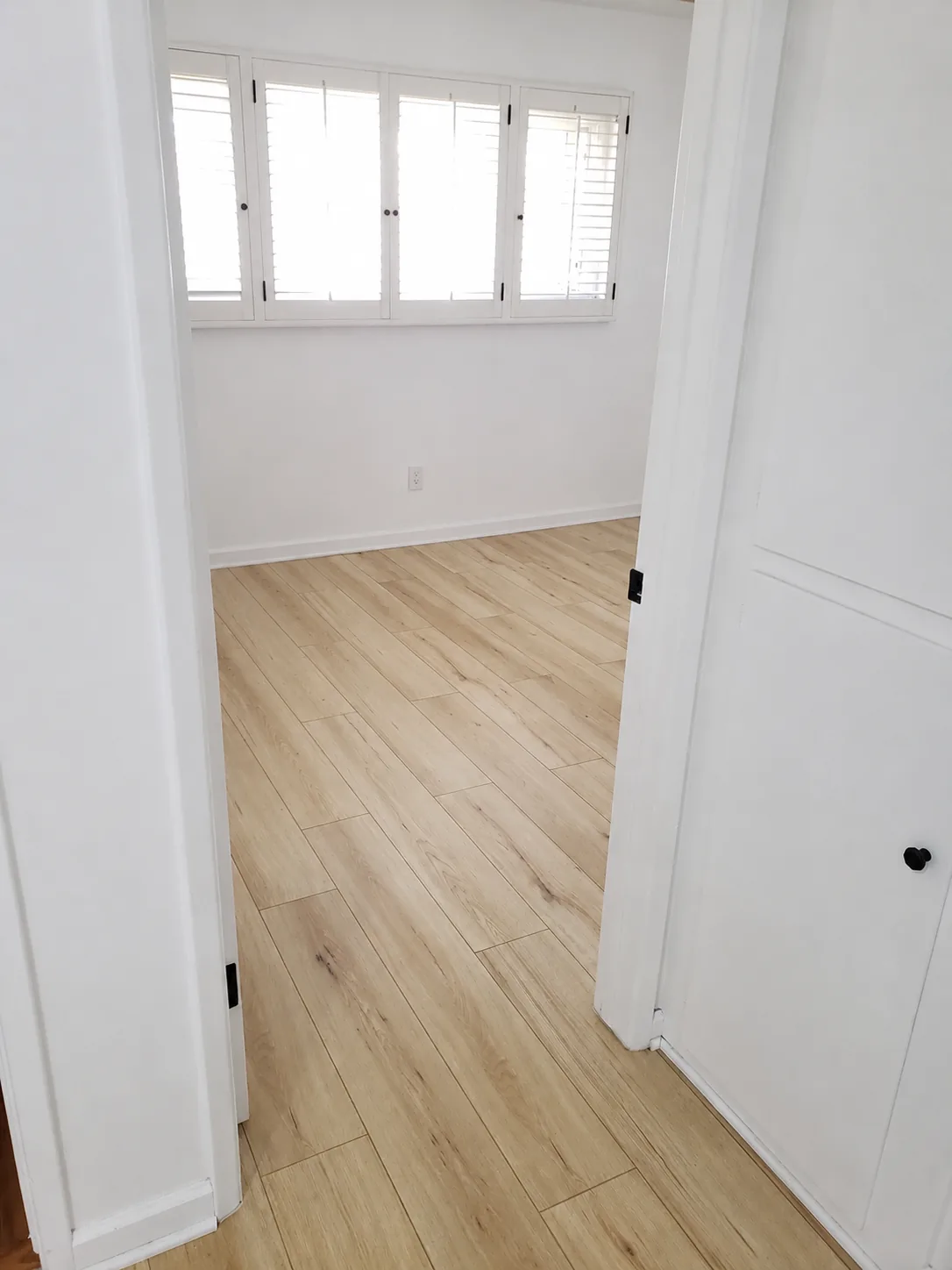 Light wood flooring installed through a bedroom doorway and hallway