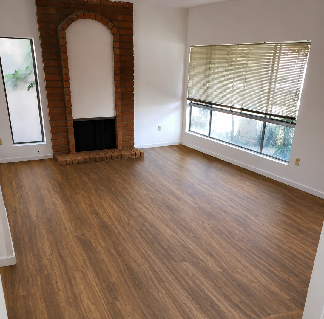 Wood flooring installed in a living room with a brick fireplace and large window